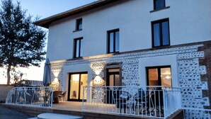 A two-story building with a balcony, a small outdoor seating area, and a staircase leading to the entrance. - Welcome to the" Domaine des étoiles"<br>Enjoy a moment of escape and fun! (GILLONNAY)