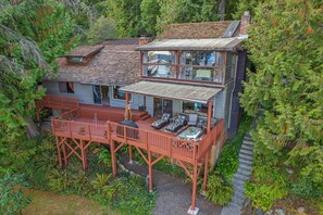 A two-story wooden house with a deck, surrounded by dense forest. - Rita s Lodge in Brinnon (Brinnon)