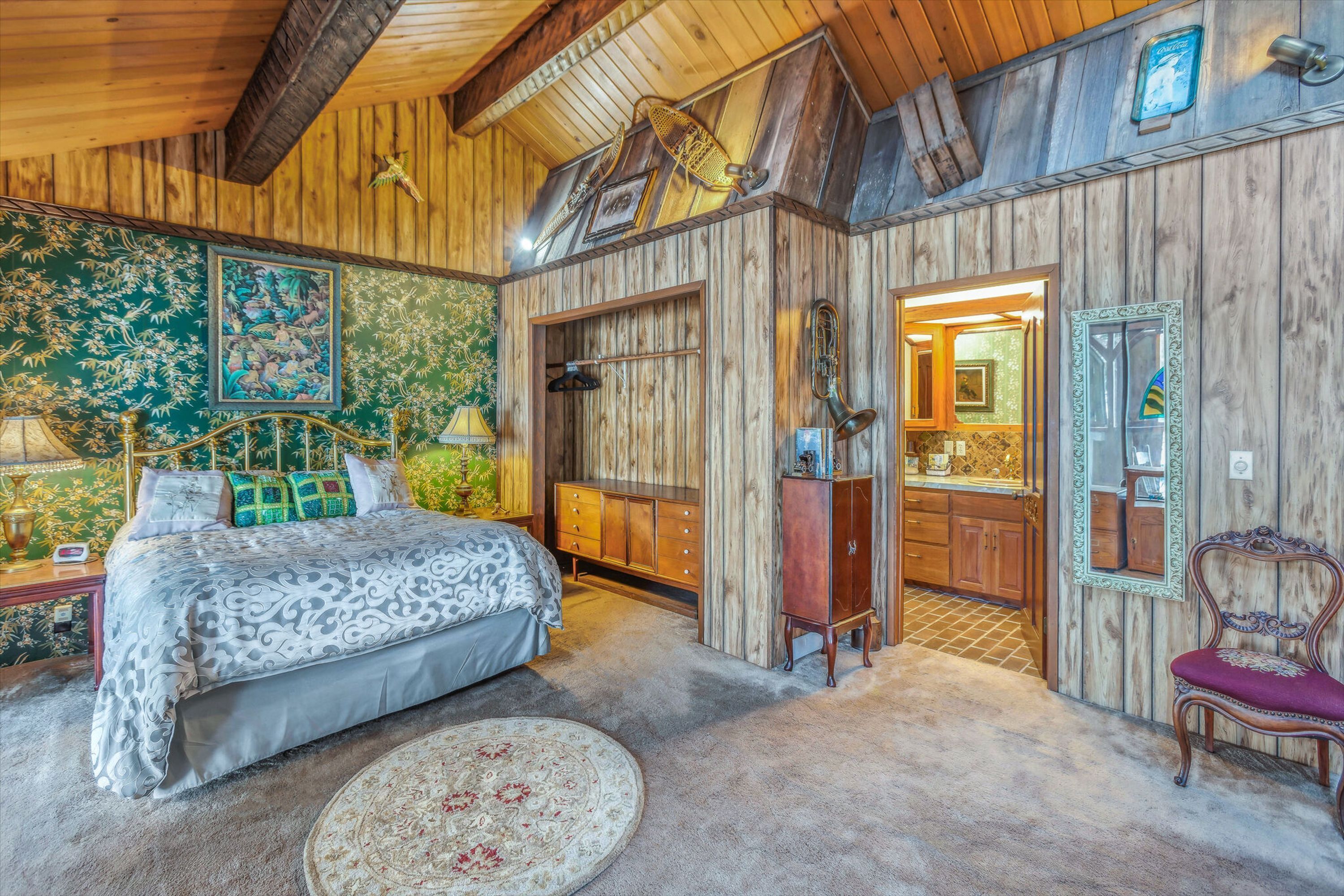 Ein rustikales Zimmer mit einem Bett, Holzwänden, einem Spiegel und einem kleinen Schrank.