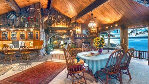 Un intérieur rustique avec un plafond en bois, un coin repas comprenant une table et des chaises, un espace cuisine et une vue sur l’océan.