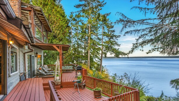 Une terrasse en bois, aménagée avec du mobilier d’extérieur, donnant sur un lac.