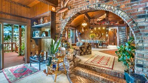 Un intérieur rustique avec une cheminée en briques, des meubles en bois et une vue sur l’extérieur.
