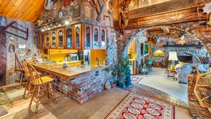 Un intérieur rustique avec un bar en briques, des chaises en bois et une cheminée.