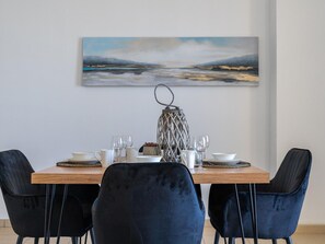 A dining area with a wooden table, two black chairs, and a decorative lantern. - JBR Beach Bliss - One & Three Bedroom Luxury Apartments by Sojo Stay (Dubai)
