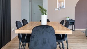 A modern dining area with a wooden table and black chairs, a potted plant, and a framed artwork on the wall. - Dubai Marina - Stunning Huge 4 Bedroom Apts Near JBR - Gym - Pool - Parking (Dubai)