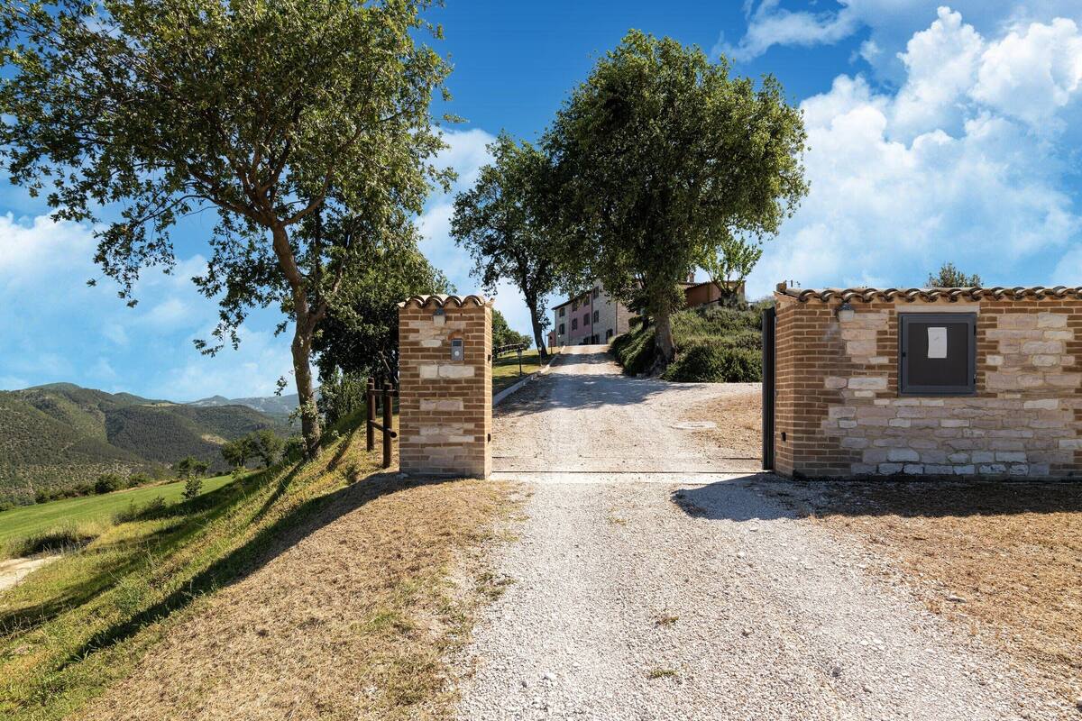 A gravel path leading to a stone gate, surrounded by trees and hills.