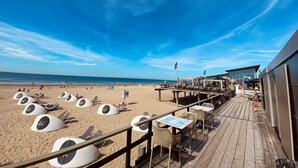 A beachside restaurant with outdoor seating and beach beds. - Apartment With Terrace With Sufficient Garden (Callantsoog)