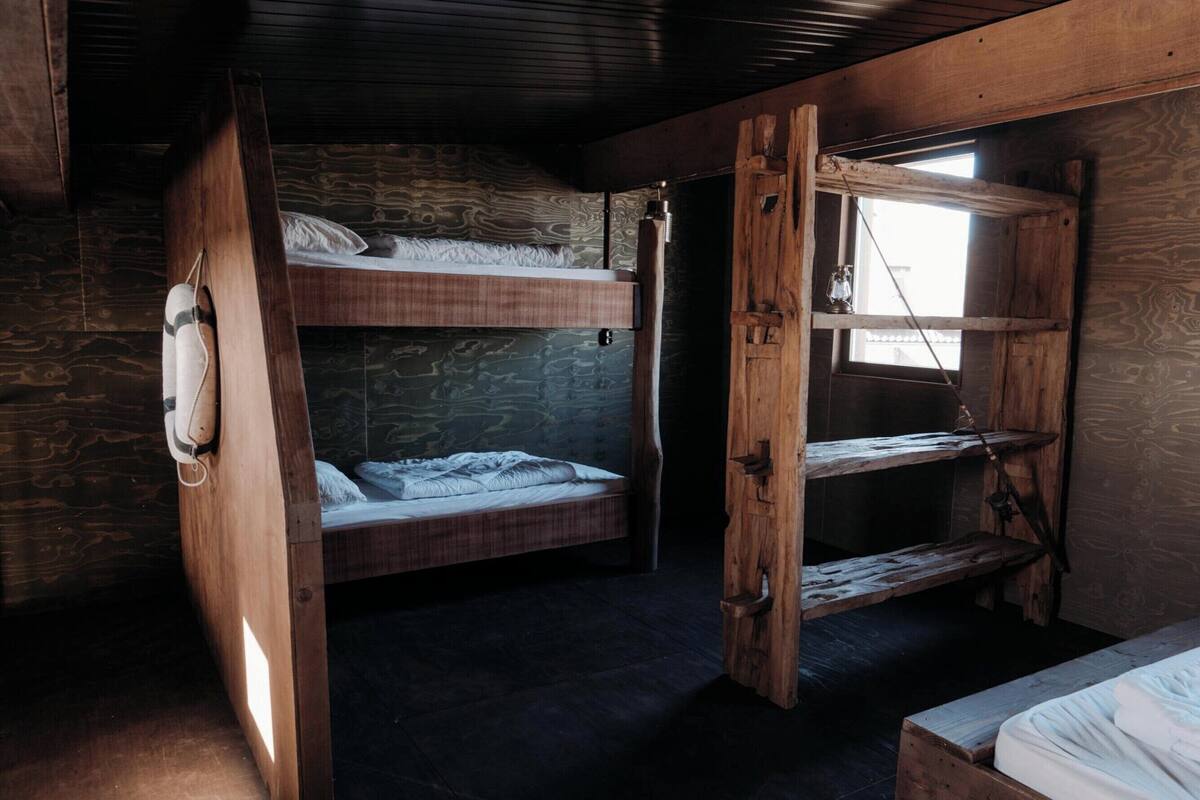 A rustic cabin with a bunk bed, a small window, and a wooden door.