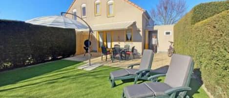 A house with a patio area featuring two lounge chairs and a table.