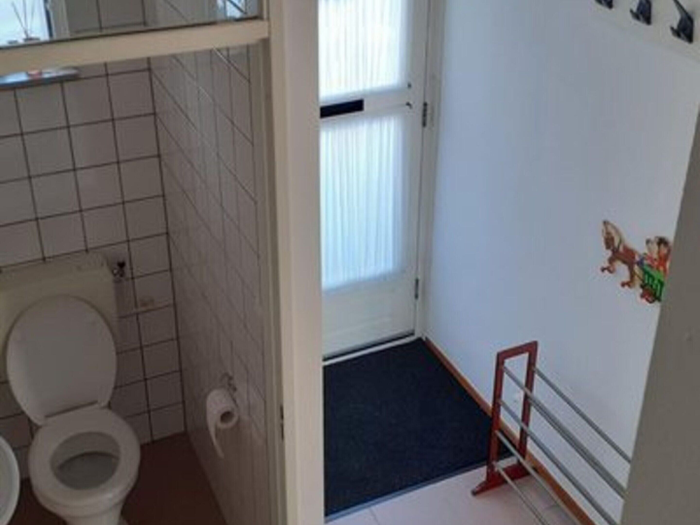A bathroom with a toilet, a towel rack, and a window.