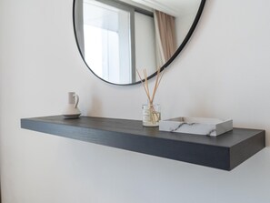 A minimalist bathroom with a dark wood floating shelf holding a white ceramic pitcher, a glass jar with reed sticks, and a marble tray. - Luxurious & Stylish Apartments Across Dubai Mall - Burj Khalifa - City Views (Dubai)