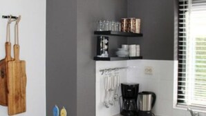 Ett kök med diskmaskin, kaffebryggare och köksredskap på bänkskivan.