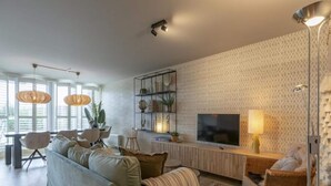 A modern living room with a sofa, chairs, a TV, and a bookshelf. - Fantastic Apartment Seaside With Terrace (Callantsoog)