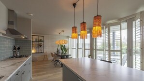 A modern kitchen with a marble countertop, a central island, and a dining area with a table and chairs. - Fantastic Apartment Seaside With Terrace (Callantsoog)