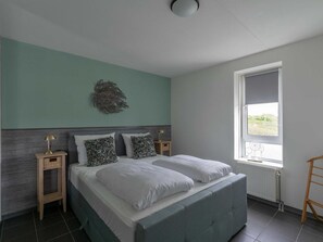 Een slaapkamer met een bed, twee nachtkastjes, een raam en een decoratief wandobject.