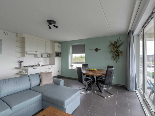Une cuisine moderne avec des meubles blancs, une table à manger avec des chaises et une grande fenêtre.