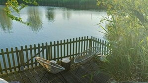 A wooden deck with two chairs and a table, overlooking a calm body of water. - Majestic Holiday Home Near Beach (Breskens)