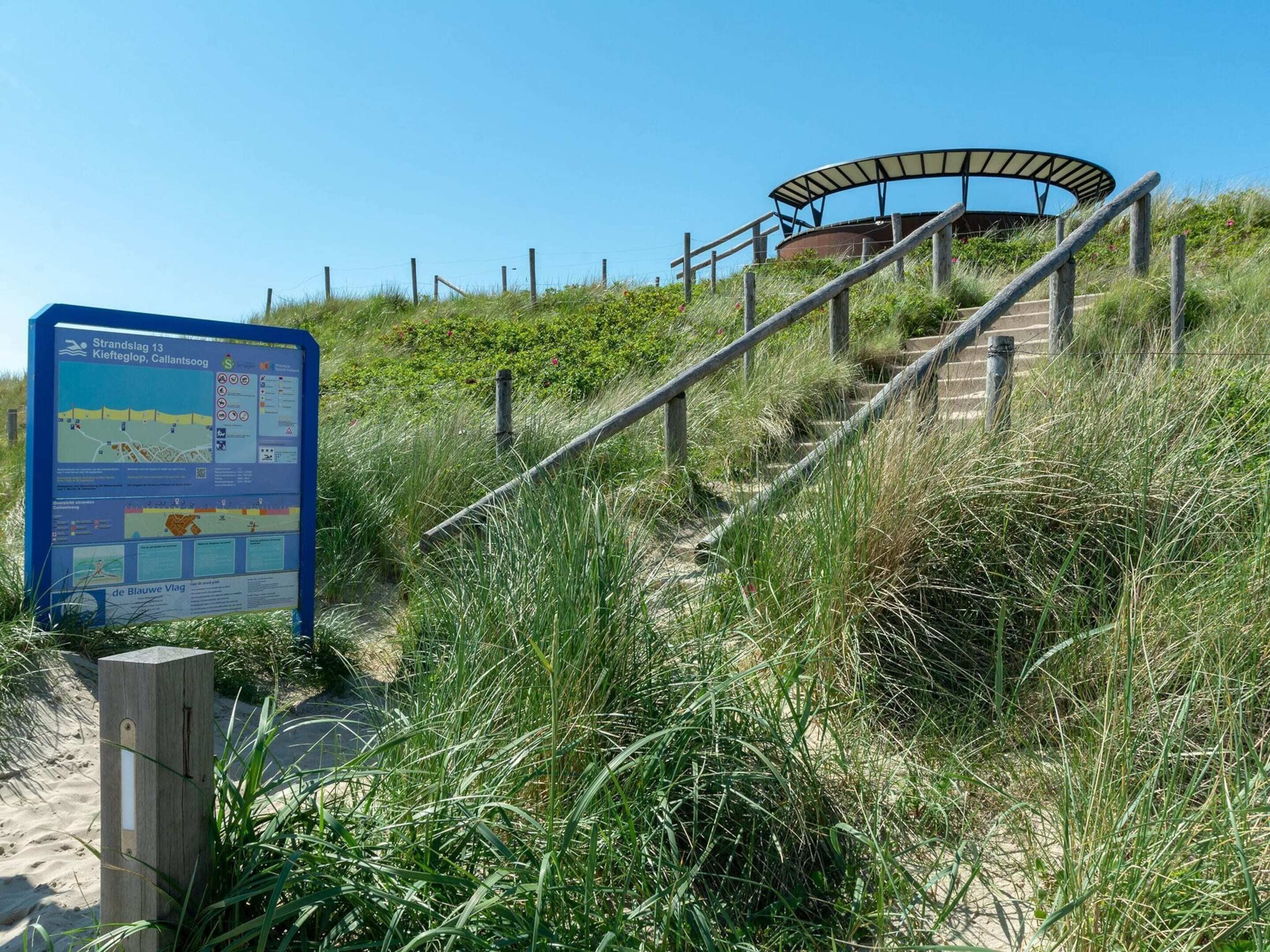 A beachside staircase leading to a covered area with a signboard in the foreground.