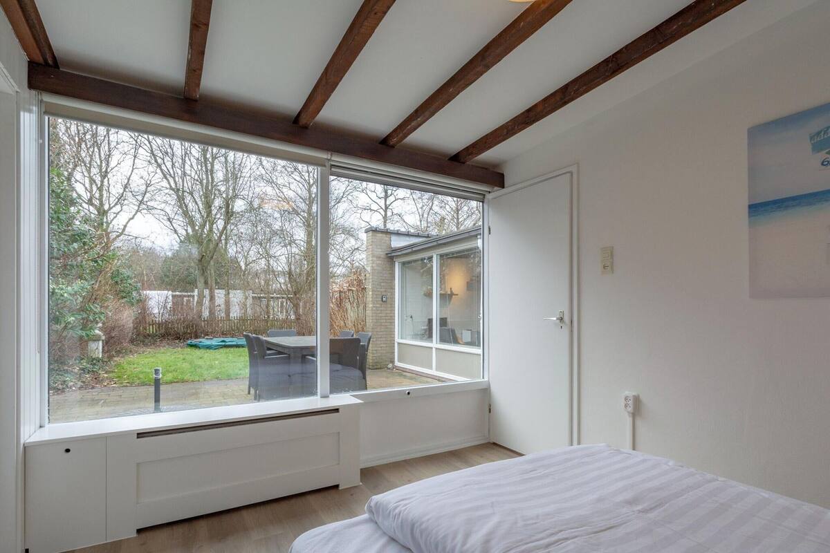 A bedroom with a large window, a bed, and a view of the outdoors.
