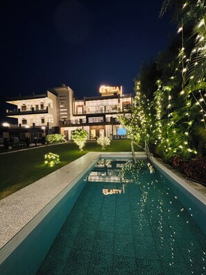 Un hôtel moderne doté d’une piscine, d’une enseigne lumineuse et d’un éclairage décoratif.