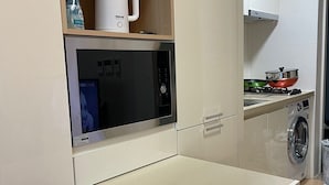 Une petite cuisine équipée d’un four à micro-ondes, d’un petit réfrigérateur, d’un évier et d’une cuisinière.