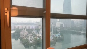 Une pièce dotée d’une grande fenêtre donnant sur un paysage urbain, avec une rivière et un pont.