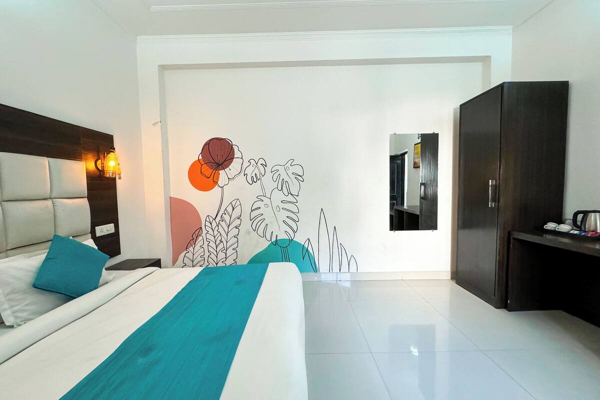 A modern hotel room with a bed, a nightstand, a wardrobe, and a wall with a decorative art piece.