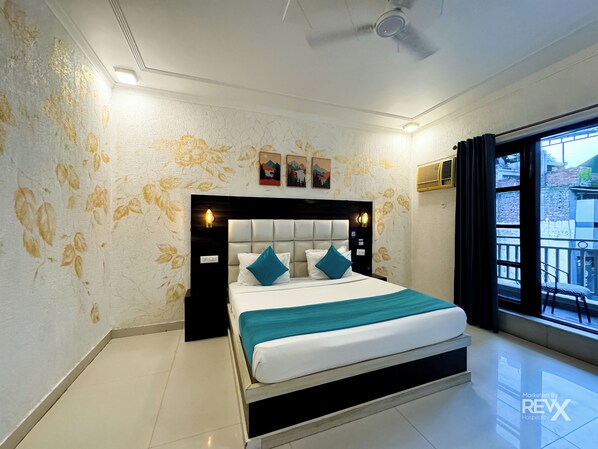 A hotel room with a bed, a ceiling fan, and a window with a view of buildings outside. - The Wraveler Tapovan Rooms and Dorms (Rishikesh)