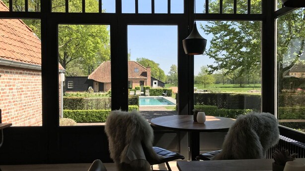 Ein Wintergarten mit Blick auf einen Swimmingpool und ein Ziegelhaus.