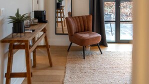 Ein modernes Wohnzimmer mit einem Holztisch, einem braunen Ledersessel und einem großen Fenster mit Gartenblick.