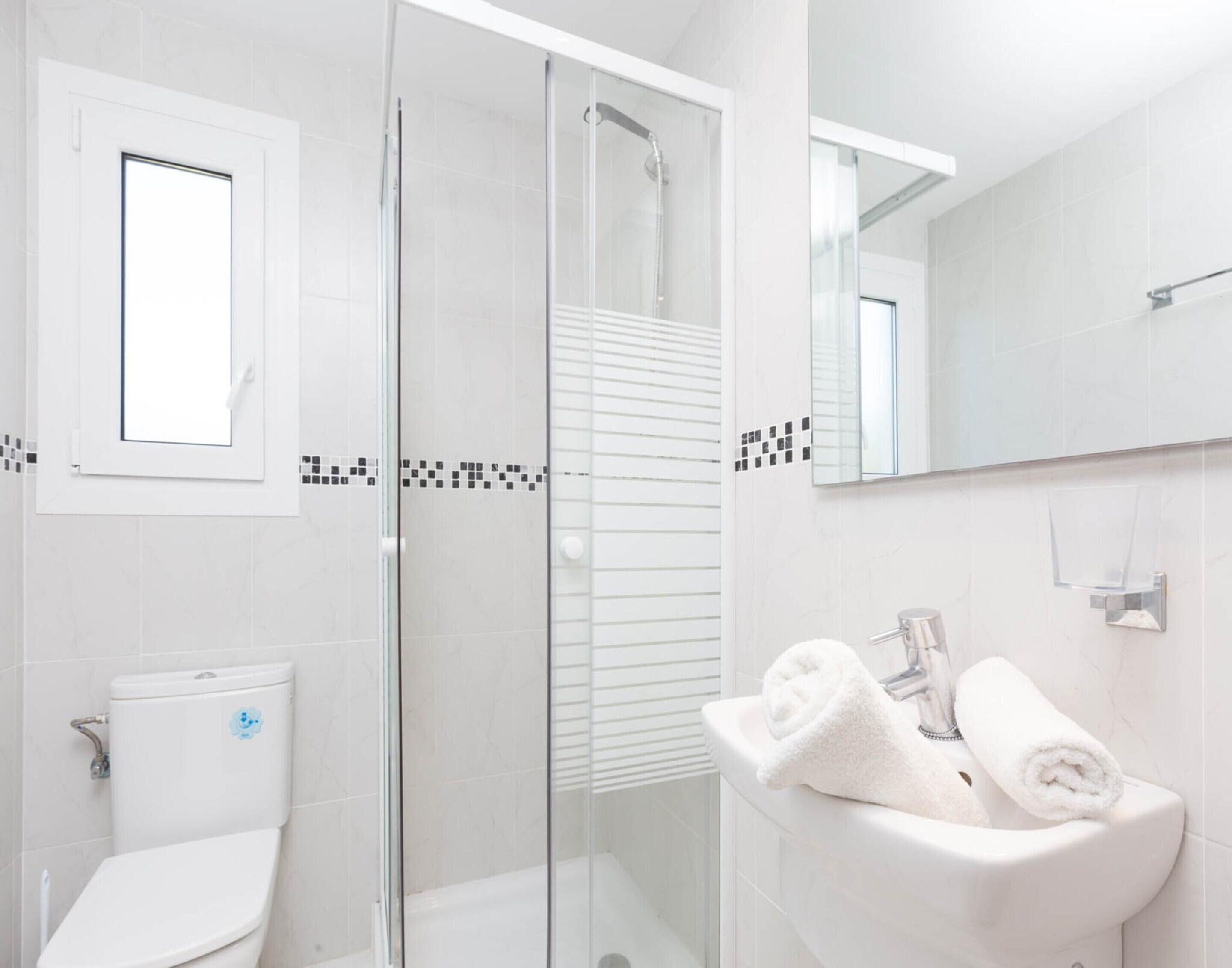 Um banheiro moderno com box de vidro, vaso sanitário e pia com porta-toalhas.