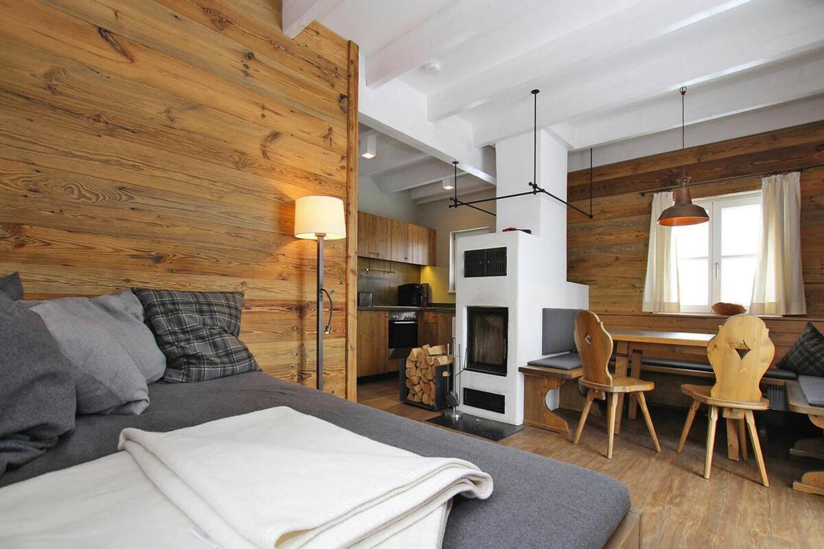 A cozy room with a bed, a wooden wall, a dining area, and a kitchen.