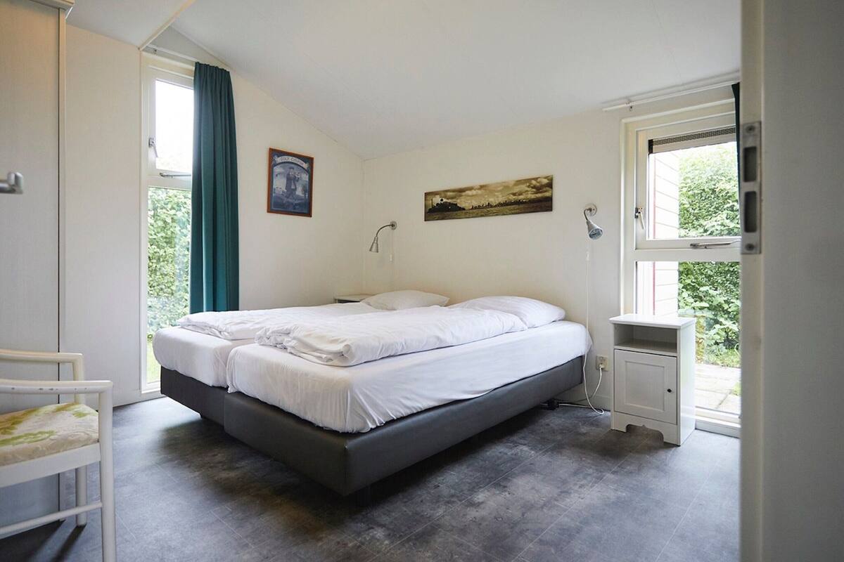 Une chambre à coucher avec un lit, une table de chevet, une fenêtre et une porte.