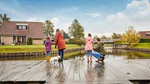 Um deck de madeira com um lago, cercado por casas.