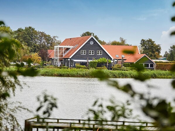 A house with a red roof and a grey facade, situated by a body of water.