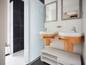 A modern bathroom with two sinks, a mirror, and a shower.