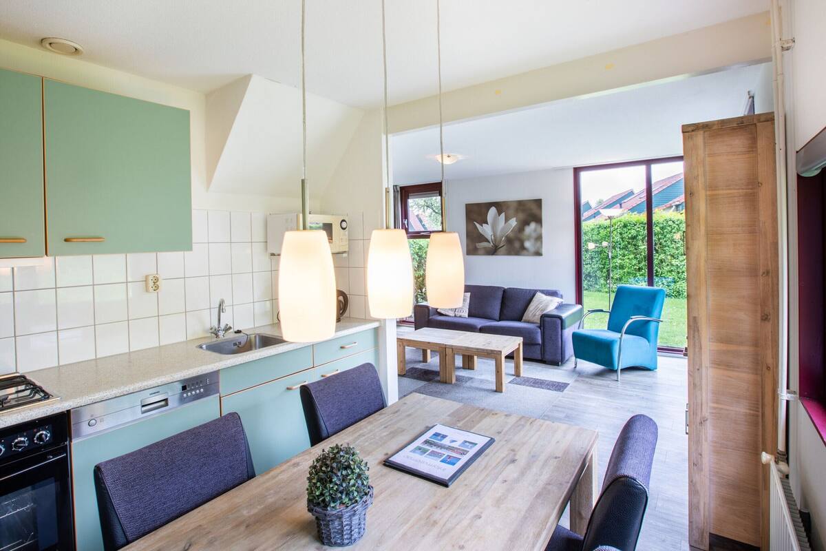 Une cuisine moderne avec un coin repas, comprenant une table en bois, des chaises et une plante en pot.