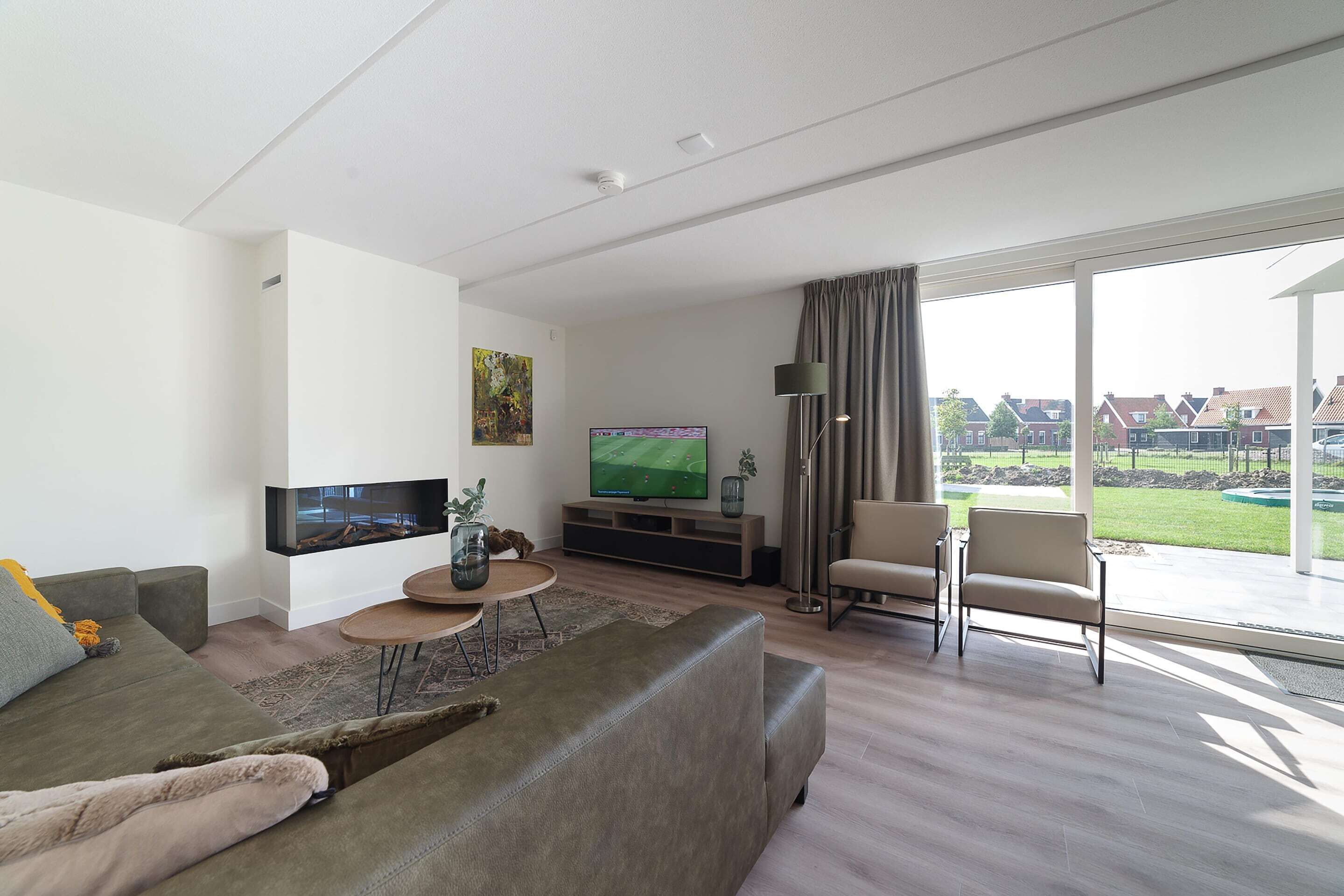Un salón moderno con televisor grande, asientos cómodos y vistas al exterior.