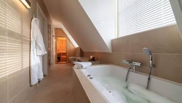 A modern bathroom with a large bathtub, a shower, and a towel rack.