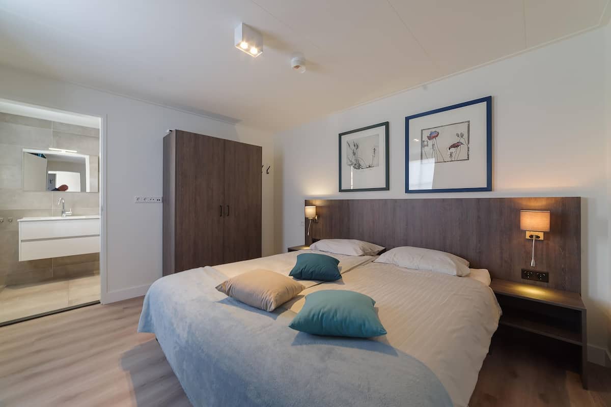 Une chambre moderne avec un grand lit, des tables de chevet et des œuvres d’art accrochées aux murs.