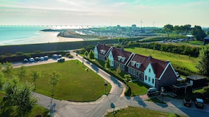 A coastal residential area with houses, a marina, and a bridge in the background. - Holiday Home With Whirlpool and Sauna in a Quiet Area in Zeeland (Colijnsplaat)