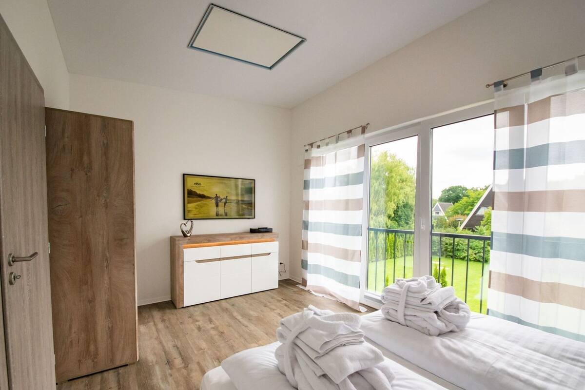 Un dormitorio con cama, una mesita de noche, un cuadro en la pared y vistas al exterior a través de una ventana.