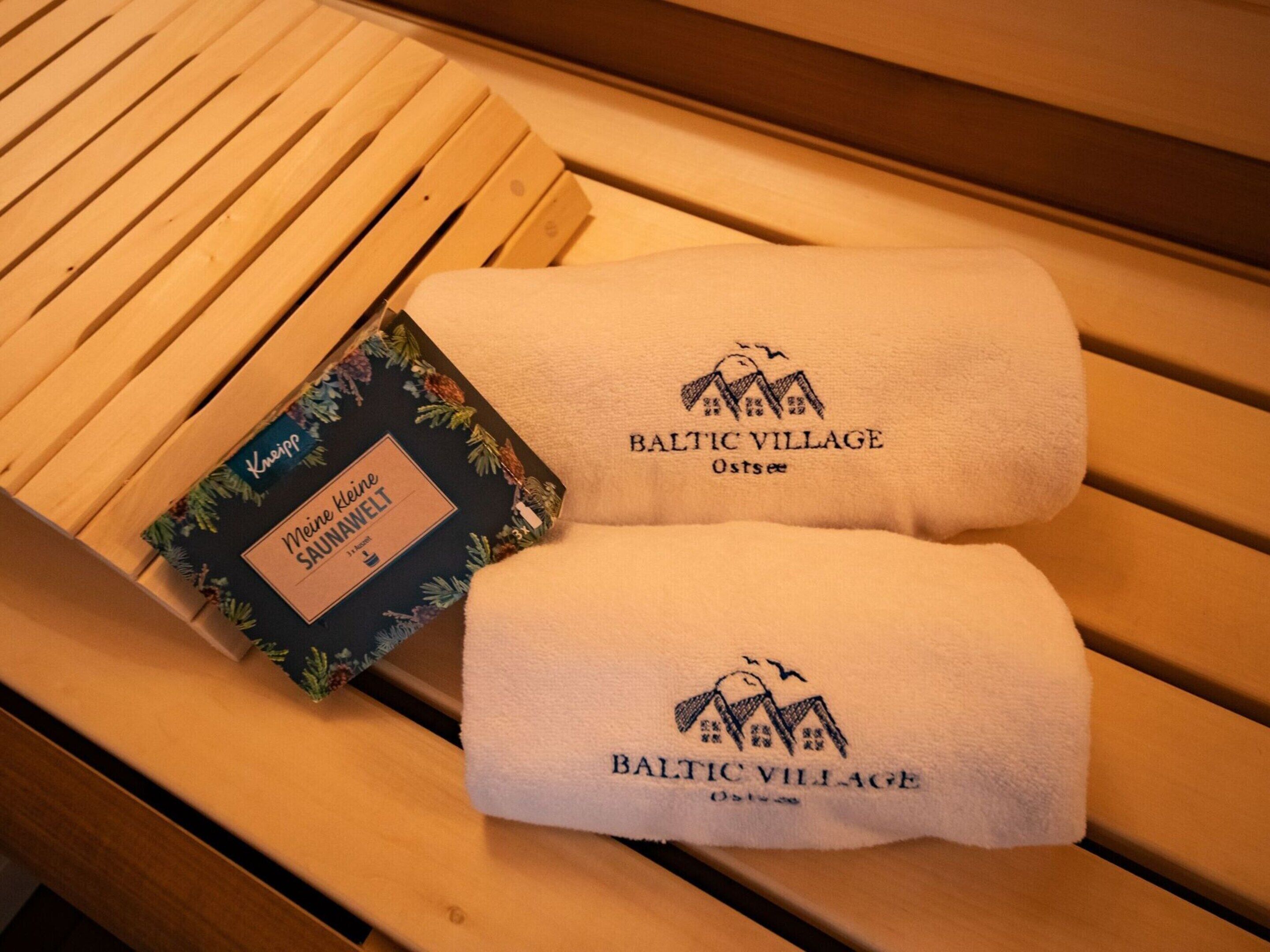Eine hölzerne Bank mit zwei Handtüchern und einem Buch.