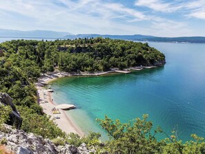 A coastal area with a beach, clear turquoise waters, and a forested peninsula. - Spacious Apartment in Dramalj With Swimming Pool (Crikvenica)