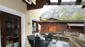 An outdoor patio with wicker furniture, a stone floor, and a view of mountains.
