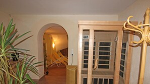 A room with a wooden sauna, a wicker basket, and a plant.