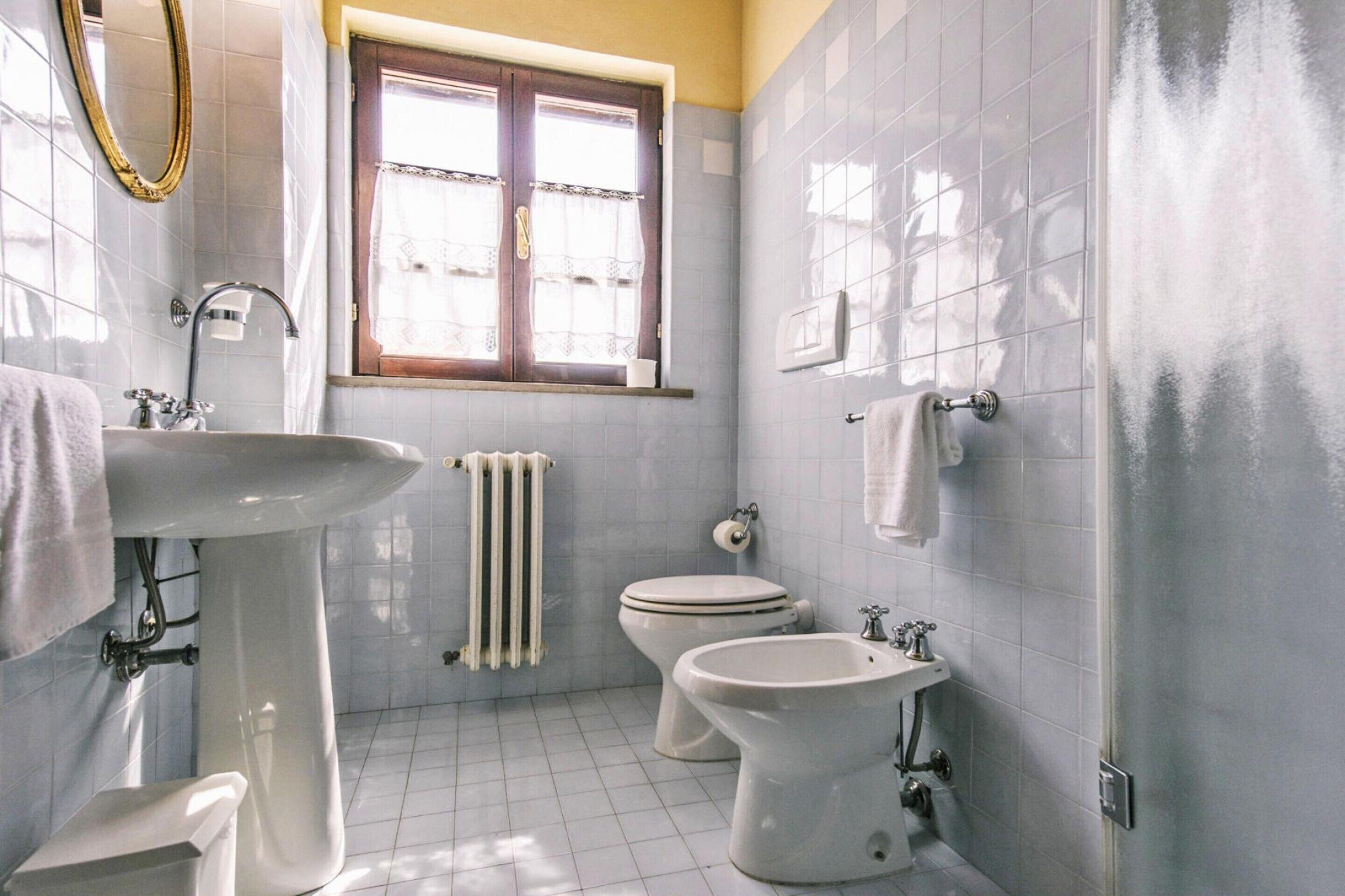 Et badeværelse med vask, bidet, toilet og et vindue.