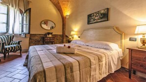 A bedroom with a large bed, a chair, a nightstand, a mirror, and a painting on the wall. - Agriturismo Tenuta Quarrata, Santo Pietro Belvedere (Capannoli)