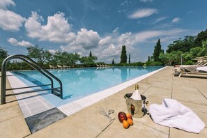 A swimming pool with a metal ladder, lounge chairs, and a bucket with fruits and a towel on the deck. - Agriturismo Tenuta Quarrata, Santo Pietro Belvedere (Capannoli)