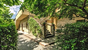 A courtyard with a stone staircase leading to an entrance, surrounded by lush greenery and a building with a stone facade. - Agriturismo Tenuta Quarrata, Santo Pietro Belvedere (Capannoli)